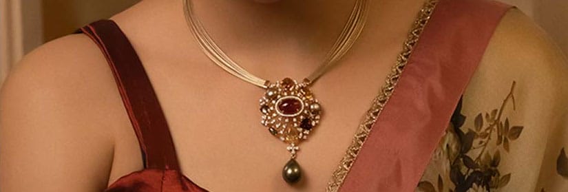 Closeup shot of a woman wearing beautiful necklace with green color stone matching with a saree.