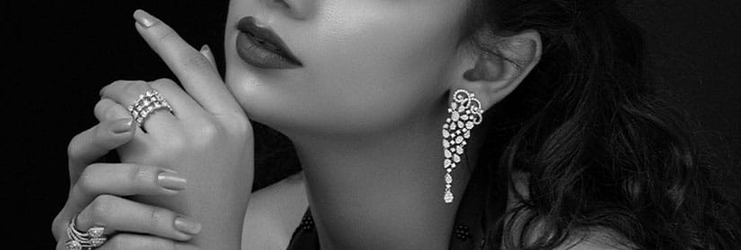 Close up shot of a woman wearing earrings and rings in a black and white picture