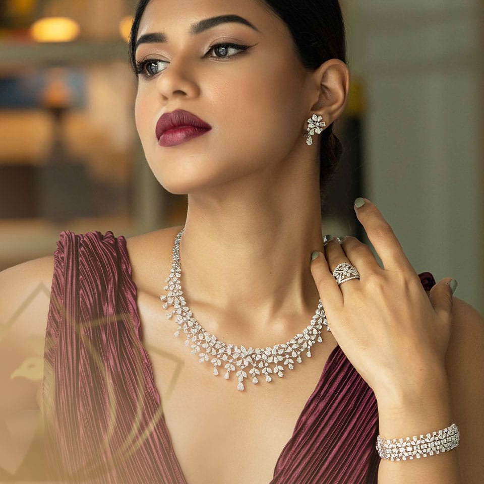 A female model with maroon top is wearing a Diamond bangles, earring, rings and necklace.