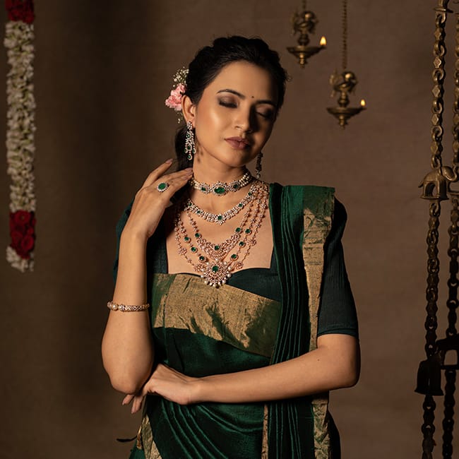 The bride wears layered diamond necklaces, diamond earrings and a diamond ring with green gemstones, and diamond bangles to match her bridal outfit.